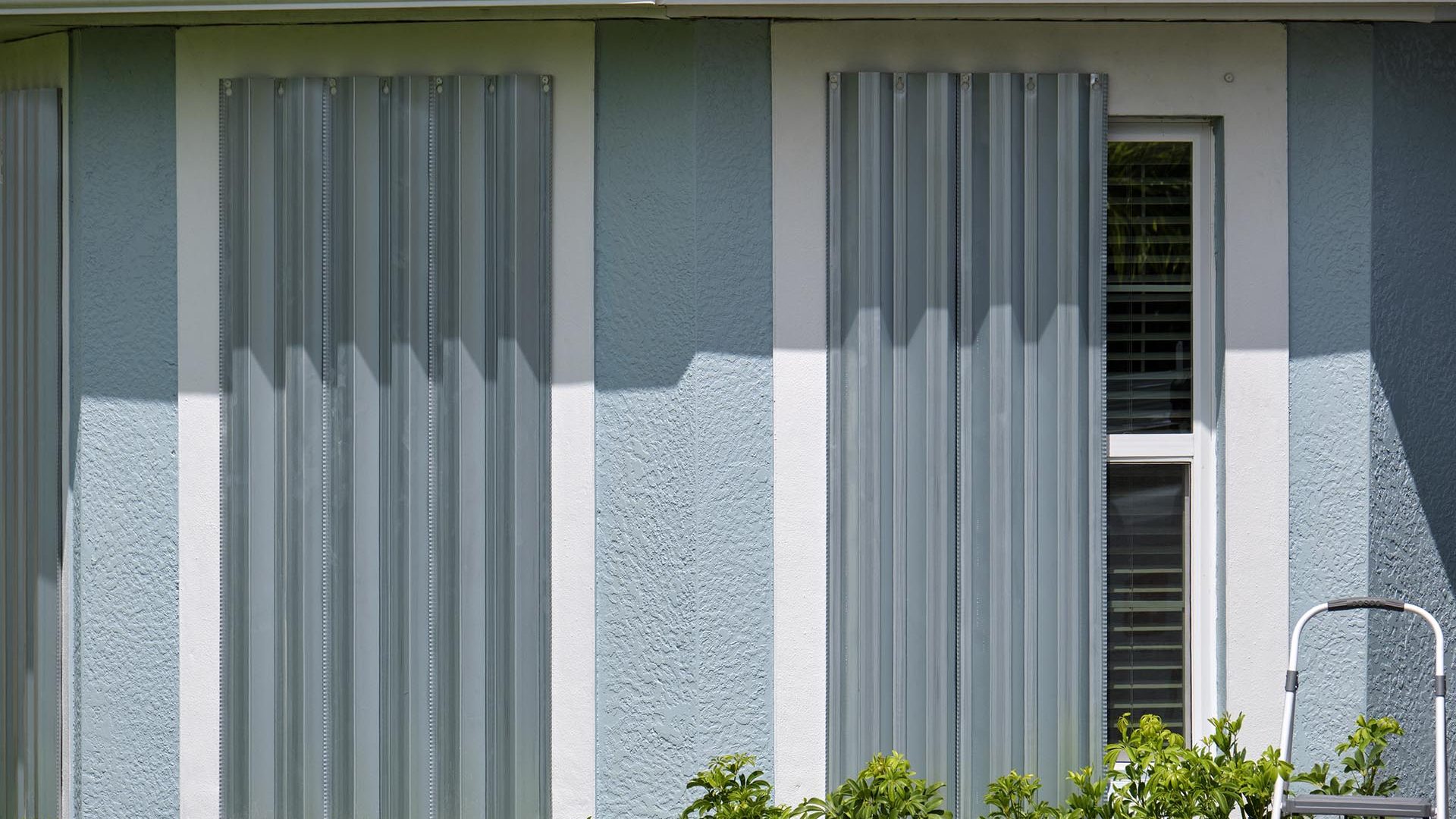 Hurricane shutters made from steel mounted for protection of house windows. Protective measures before natural disaster in Florida.